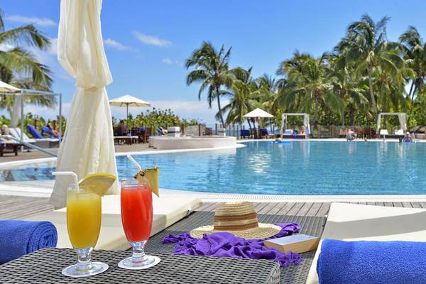 Pool-Loungebereich im Melia Las Americas Hotel mit Cocktails und Sonnenschirmen.