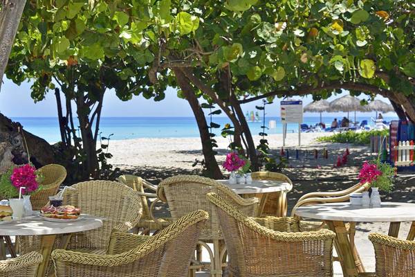 Sitzplätze am Strand des Melia Las Americas Hotels mit Blick auf das Meer und Palmen