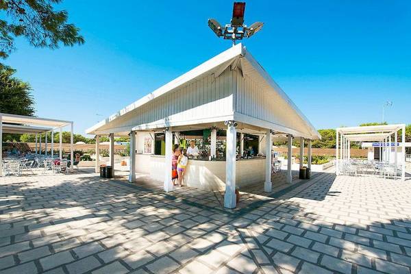 Außenbereich der Bar im VOI Alimini Resort mit weißen Strukturen und Sonnenschutz.
