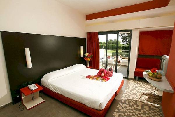 Hotelzimmer des VOI Alimini Resort mit rotem Bett und Blick auf Garten
