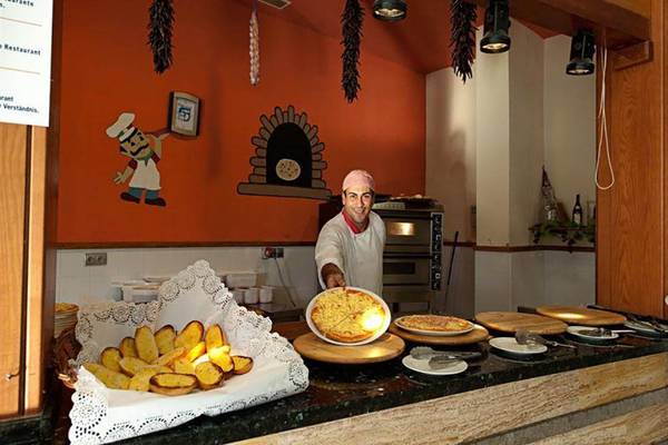 Mitarbeiter im LIVVO Lago Taurito Hotel serviert Pizzas an einem Tresen.
