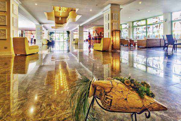 Lobby des DAS Club Hotel Sunny Beach mit großen gelben Stühlen und einem kunstvollen Brunnen.