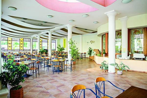Innenbereich des DAS Club Hotel Sunny Beach mit vielen Tischen und Stühlen, Säulen und Pflanzen.