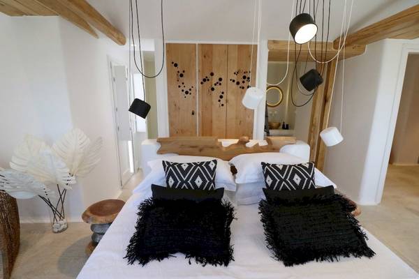Schlafzimmer im Alkyoni Beach Hotel mit weißem Bett, schwarzen Kissen und Holzelementen.