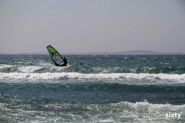 Eine Person windsurft in stürmischem Ozean mit hohen Wellen.