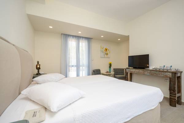 Schlafzimmer im Alkyoni Beach Hotel mit zwei Betten, Fernseher und Dekor.