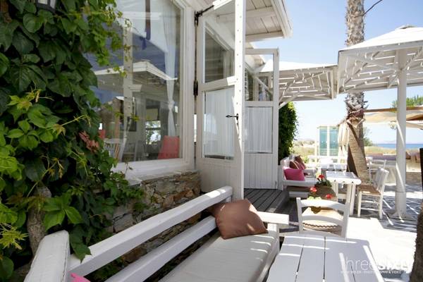 Außenbereich des Alkyoni Beach Hotels mit weißer Terrassenmöbeln und grünen Pflanzen.