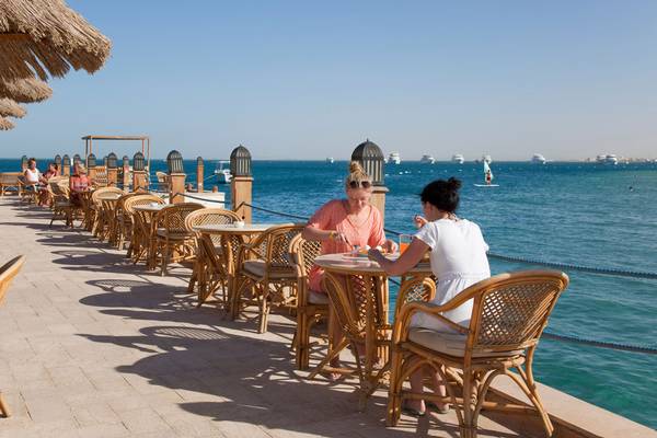Foto von Gästen, die an Tischen auf der Terrasse des Siva Grand Beach Hotels am Wasser sitzen