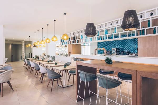 Innenansicht des Restaurants im Iberostar Selection Sabila Hotel mit Tischen, Stühlen und Bar.