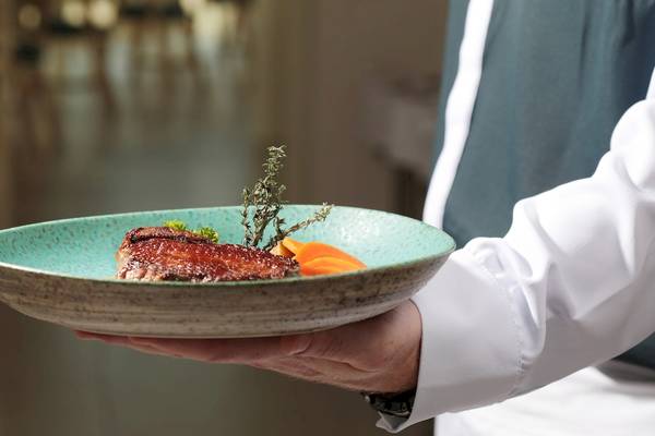 Ein Kellner hält eine Platte mit einem gebratenen Gericht und Beilagen im Iberostar Selection Sabila Hotel.