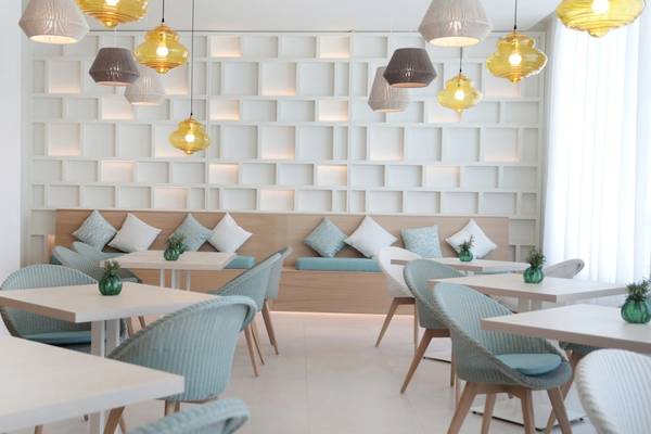 Innenraum des Iberostar Selection Sabila Hotels mit weißen Tischen, blauen Stühlen und dekorativen Lampen.
