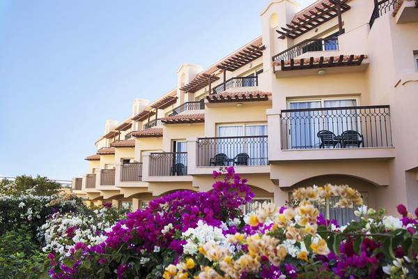 Außenansicht des Pyramisa Beach Resort Sahl Hasheesh mit mehreren Balkonen und bunten Blumen davor.