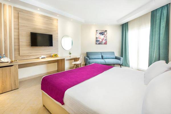 Innenansicht eines Hotelzimmers im Pyramisa Beach Resort Sahl Hasheesh mit Bett, Sofa, Fernseher und Schreibtisch.