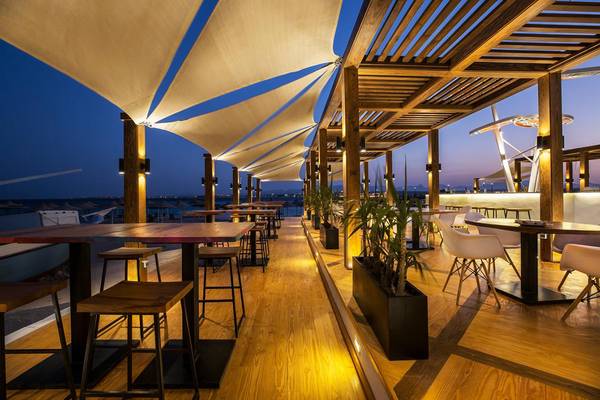 Terrasse des Pyramisa Beach Resort Sahl Hasheesh bei Nacht mit Tischen und Stühlen.