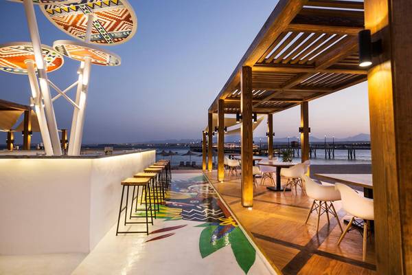 Terrasse des Pyramisa Beach Resort Sahl Hasheesh mit Tischen, Stühlen und bunten Bodendesign.