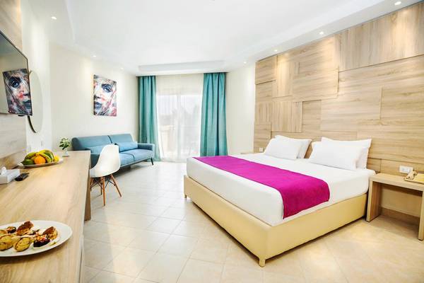 Interieur des Pyramisa Beach Resort Zimmers mit Bett, Sofa, Tisch und Früchten.