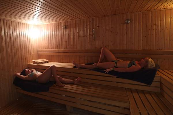 Zwei Frauen entspannen sich in einer holzgetaefelter Sauna