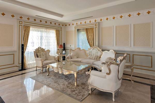 Wohnzimmer im Rixos Premium Bodrum Hotel mit weißen Möbeln und goldenen Akzenten.