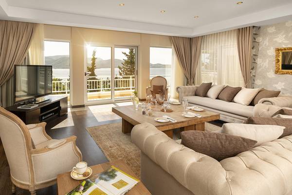 Wohnzimmer mit Meerblick im Rixos Premium Bodrum Hotel, mit Sofas, Tisch, Fernseher und Panoramafenstern.