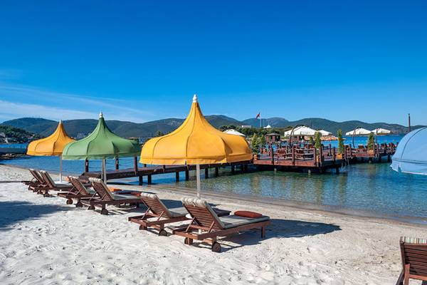 Strand mit Sonnenliegen und Umbrellas im Rixos Premium Bodrum Hotel