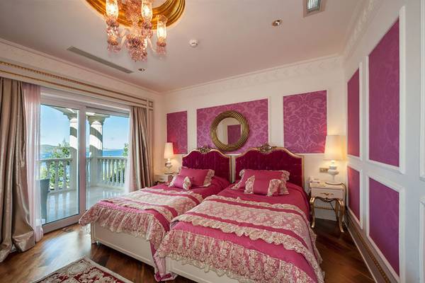 Schlafzimmer im Rixos Premium Bodrum mit zwei Betten, pinken Wänden und einer Terrasse mit Meerblick.