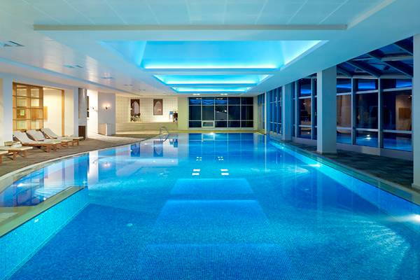Innenpool des Rixos Premium Bodrum mit blauen Wänden und Decke, Lounge-Sesseln und großen Fenstern.
