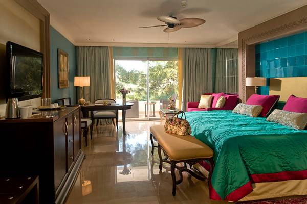 Luxuriöse Suite im Rixos Premium Bodrum mit großem Bett, Wohnzimmermöbeln und Blick auf den Garten.