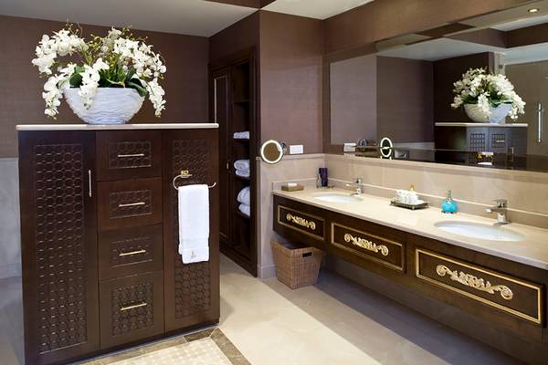 Luxuriöses Badezimmer im Rixos Premium Bodrum mit Doppelwaschbecken, Spiegel und Blumenvase.