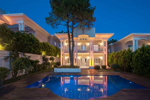 Nachtansicht der Rixos Premium Bodrum Villa mit beleuchtetem Pool und Bäumen.
