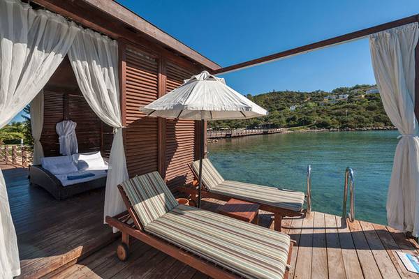 Terrasse mit zwei Liegen und einem Sonnenschirm im Rixos Premium Bodrum.