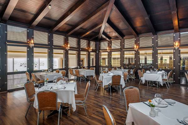 Innenansicht des Restaurants im Rixos Premium Bodrum mit gedeckten Tischen und hölzernem Interieur.