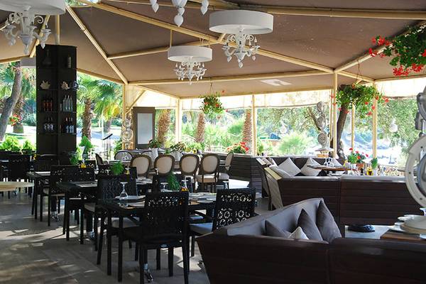 Restaurant im Rixos Premium Bodrum mit Tischen, Stühlen und Deckenlampen.