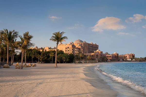 Emirates Palace Mandarin Oriental Hotel am Strand mit Palmen und Gebäuden im Hintergrund