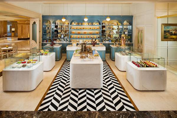 Innenansicht des Patissiers im Emirates Palace Mandarin Oriental mit weißen Marmortischen und blauen Schränken, gefüllt mit verschiedenen Süßigkeiten.
