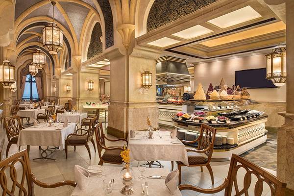 Innenbereich des Restaurants im Emirates Palace Mandarin Oriental mit eleganten Tischen, Stühlen und einer großen Speisetheke.