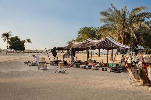 Ein Kamel-Stall am Strand des Emirates Palace Mandarin Oriental mit einem Verkäufer unter einem Zelt.