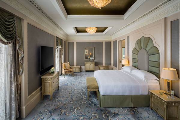 Schlafzimmer im Emirates Palace Mandarin Oriental mit großem Bett, Fernseher, Schränken und Dekor.