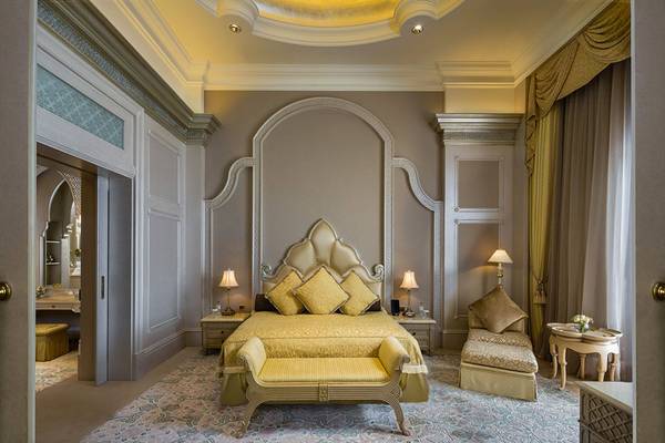Schlafzimmer im Emirates Palace Mandarin Oriental Hotel mit einem großen Bett, gelben Kissen und einem aufwendigen Kopfteil.