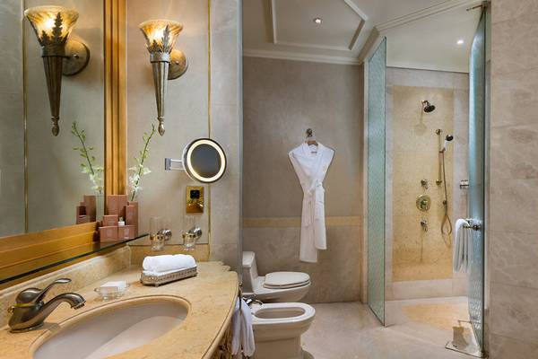 Das Badezimmer des Emirates Palace Mandarin Oriental mit einer Dusche, Toilette und Waschbecken.