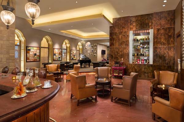 Interieur des Emirates Palace Mandarin Oriental mit Loungebereich, Ledersesseln, Bar und Klavier.