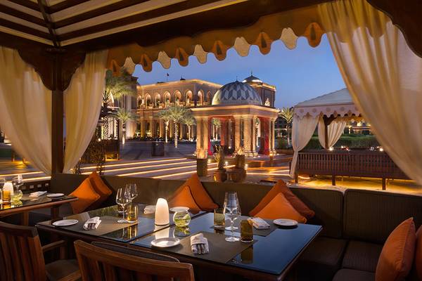 Außenbereich des Restaurants im Emirates Palace Mandarin Oriental, beleuchtet in der Nacht mit Gebäude im Hintergrund.