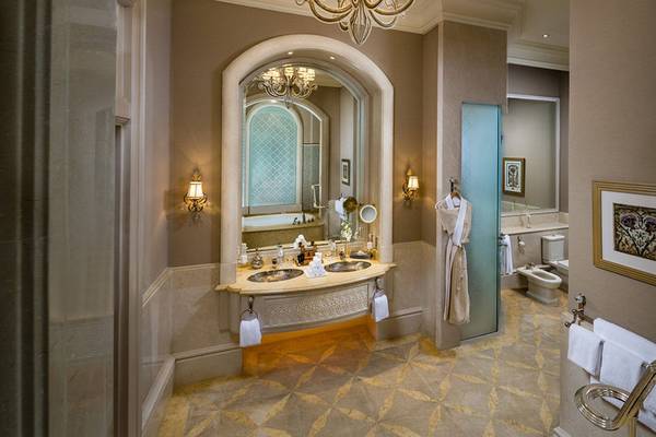Ein Badezimmer im Emirates Palace Mandarin Oriental mit einem großen Spiegel, einem Doppelwaschbecken und einem Badewannenbereich.