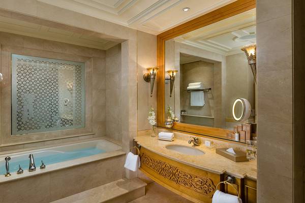 Badezimmer im Emirates Palace Mandarin Oriental mit Badewanne, Spiegel und Waschtisch.