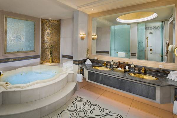 Luxuriöses Badezimmer im Emirates Palace Mandarin Oriental mit Whirlpool, zwei Waschbecken und großem Spiegel.