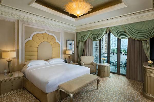 Schlafzimmer im Emirates Palace Mandarin Oriental mit Bett, Nachttischen, Lampe, Sessel und Fernseher.