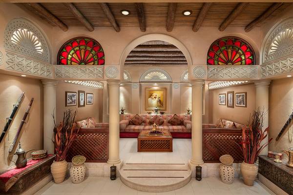 Inneneinrichtung des Emirates Palace Mandarin Oriental mit gepolsterten Sofas, Säulen, bunten Fenstern und dekorativen Elementen.