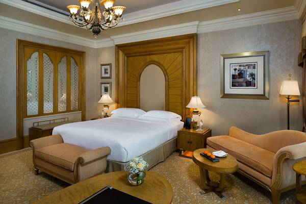 Schlafzimmer im Emirates Palace Mandarin Oriental mit Bett, Sesseln und Dekoration.