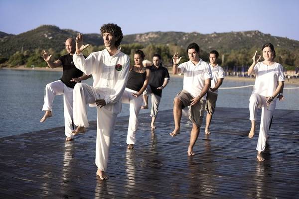 Gruppe von Menschen, die Yoga auf einem Steg am Wasser am Park Hotel Cala di Lepre machen.