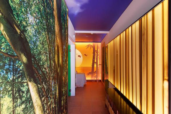 Korridor des Parque Tropical Hotels mit Wandgestaltung, die einen Wald und eine Sonnenuntergangsszene darstellt.