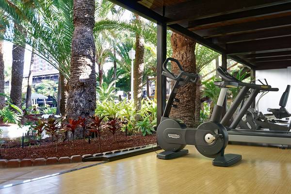 Fitnessgeräte im Fitnesscenter des Parque Tropical Hotels neben einem Garten
